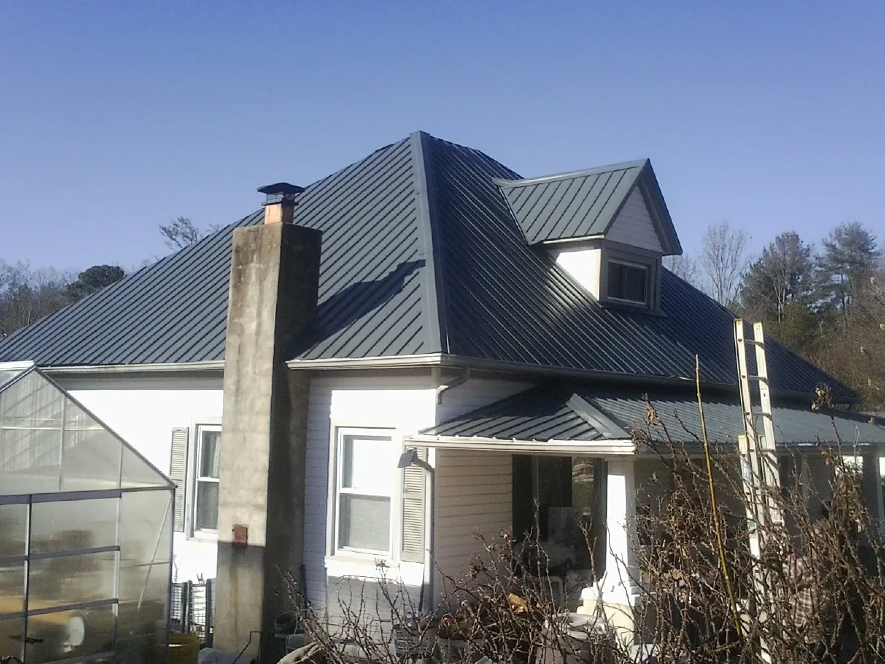 Dark blue standing seam metal roof on a white farmhouse with dormer — Slate & Tile Roof Repair by Roofing Brothers in Marianna