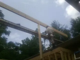 Carpenter setting a ridge beam over a new addition frame — Ice Dam Removal by Roofing Brothers in Marianna